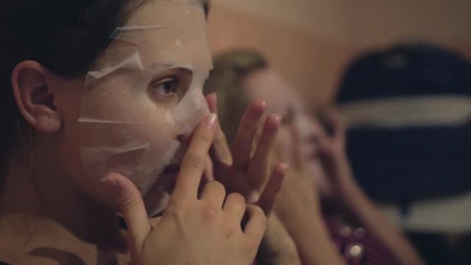 两名妇女在脸上涂上日本化妆品薄纸面膜，使脸上的面膜光滑。
