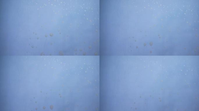 蓝色背景上流动的肥皂产生泡沫。