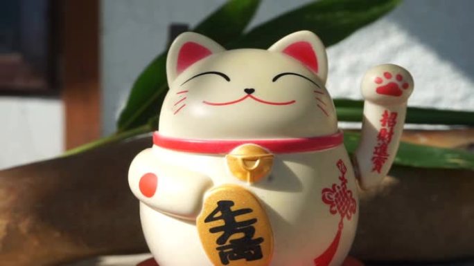 日本玩具招财猫雕像，持有日语金牌，翻译成繁荣和好运。在外面的气氛中，有阳光。