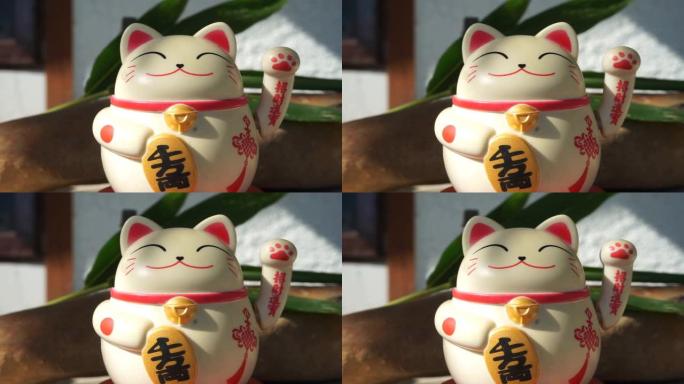 日本玩具招财猫雕像，持有日语金牌，翻译成繁荣和好运。在外面的气氛中，有阳光。