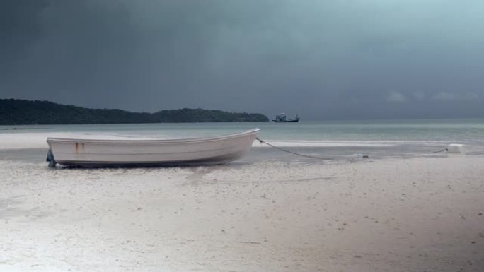白色海滩上的一艘小船的特写镜头，背景中隐约可见黑暗的季风风暴