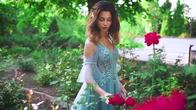 穿着豪华水彩服的女王在开花的夏季花园里散步。