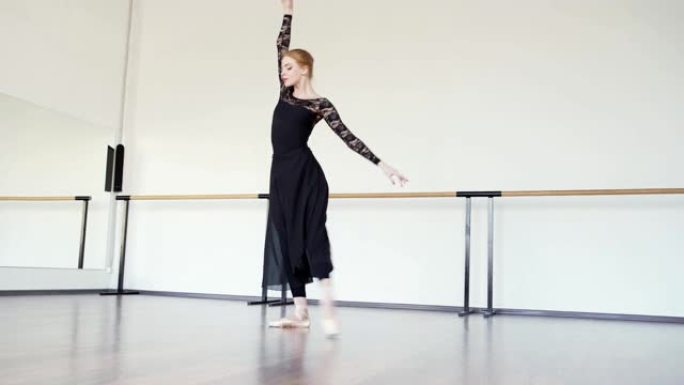 优美的职业芭蕾舞演员穿着脚尖鞋，黑色紧身连衣裤和长裙在芭蕾舞工作室排练