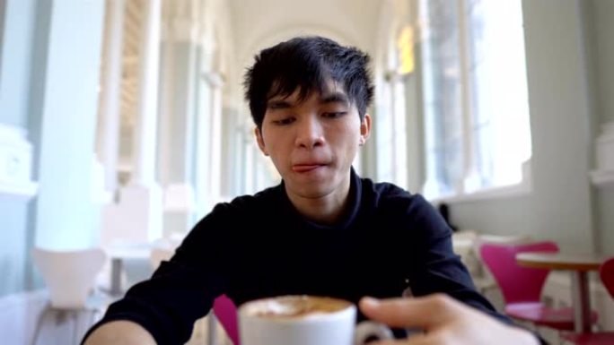 年轻的亚洲男子早上在自助餐厅喝热咖啡