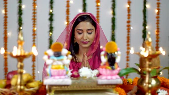 漂亮的印度女性在排灯节上在印度教神拉克希米和甘尼什面前祈祷