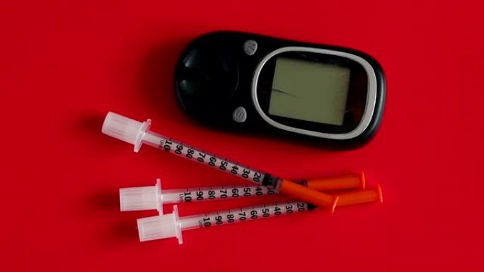 用于在红色背景上测量血糖的胰岛素注射器和血糖仪。
