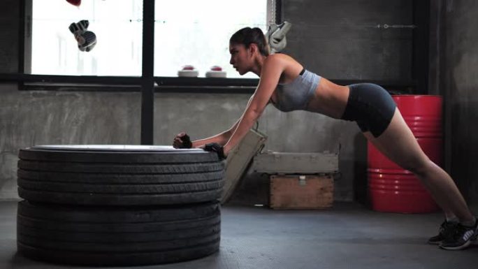 亚洲年轻运动型女性在健身房进行腹肌锻炼，进行交替的身体提升和铺板锻炼。
