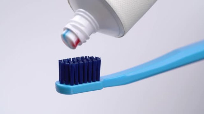 将三种颜色的牙膏从管子上挤压到牙刷上。孤立在白色背景上。特写。宏观。