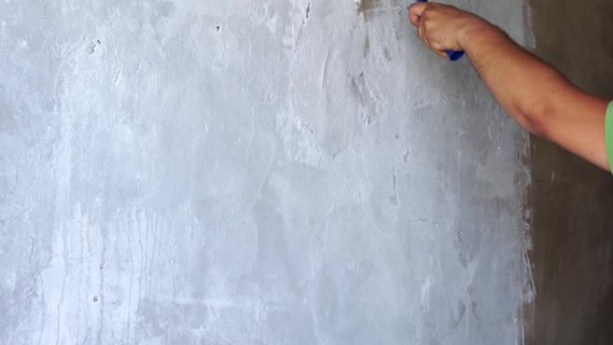 用白色油漆滚筒粉刷旧墙