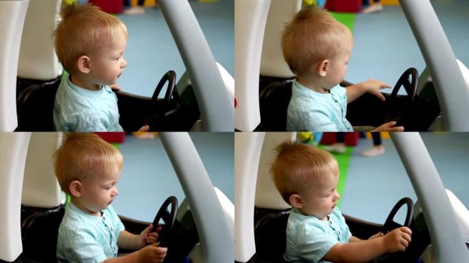 坐在玩具车里的男孩。婴儿关上车门开车。儿童游戏中心的孩子。