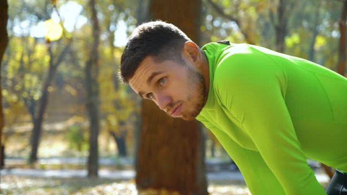 英俊的运动员在秋季公园慢跑后呼吸困难