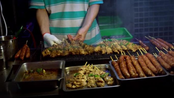 慢动作摊贩用棍子烹饪台湾鸡肉。夜市街。