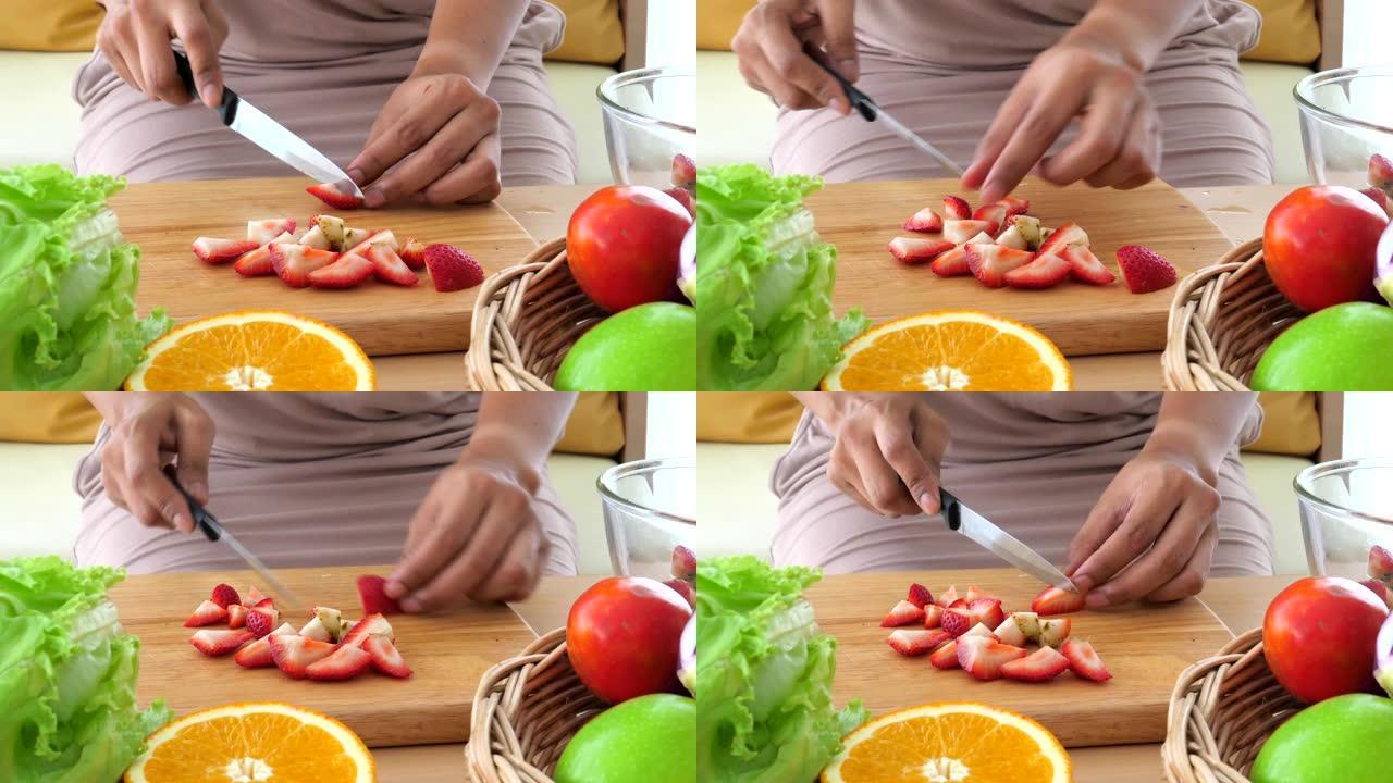 女人用蔬菜和水果切成红色草莓以制作健康沙拉的特写镜头。食物烹饪和配料。生酮饮食概念。人们的生活方式和