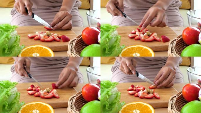 女人用蔬菜和水果切成红色草莓以制作健康沙拉的特写镜头。食物烹饪和配料。生酮饮食概念。人们的生活方式和