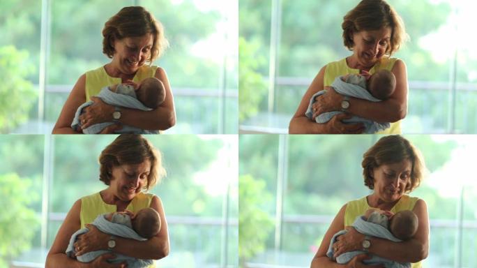 快乐的祖母平静并将新生婴儿抱在怀里
