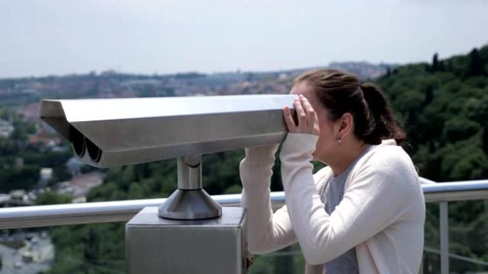 女人透过双筒望远镜探索海湾的城市景观