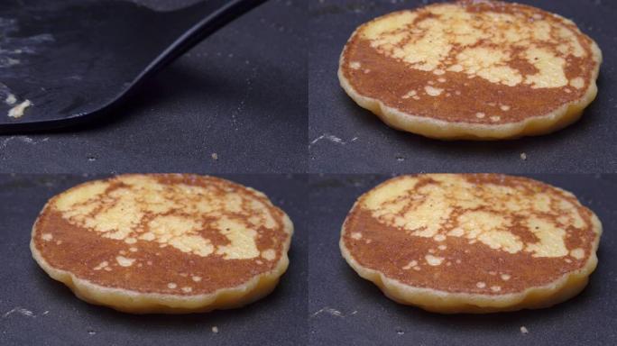 用抹刀在热煎锅中翻转煎饼，用融化的黄油拍摄女子手的4k特写镜头。制作煎饼自制食谱煎饼，为家庭美味早餐