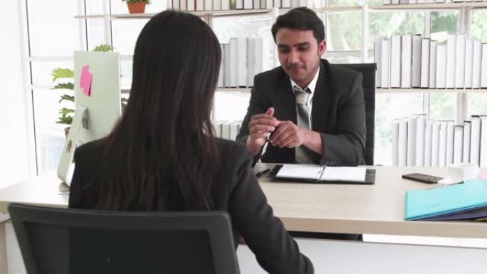 两个穿着黑色西装的商人男人和亚洲女人坐在办公室里聊天，在商务会议上用名片介绍并握手成交