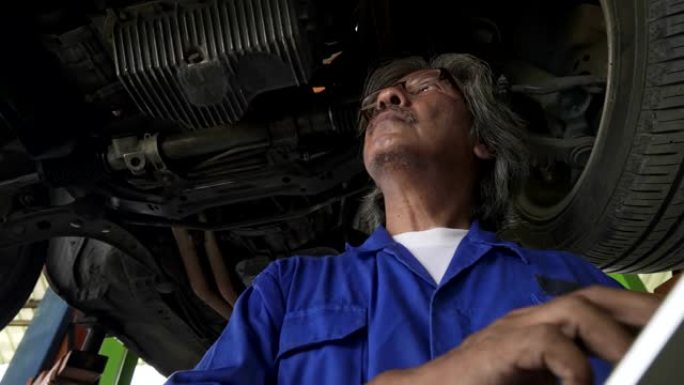 亚洲高级汽车修理工检查发动机和电气系统的状况，记录在清单上。检查发动机油位，检查电保险丝。检查漏油和