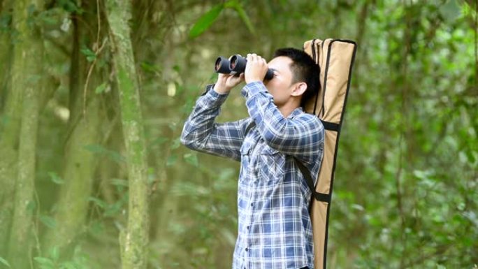 用双筒望远镜在森林里的人看起来像迷失的人或可预见的未来。人们的生活方式和休闲活动理念。自然和背包客旅