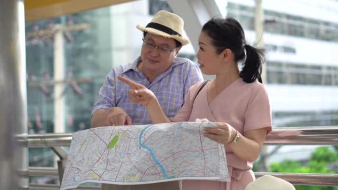 快乐的亚洲老年夫妇游客旅行时看着地图，指着户外城市的目的地。老人旅行者的生活方式。老年妇女度假。老龄