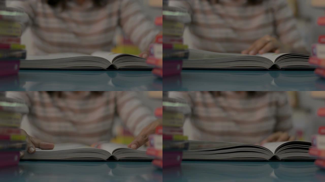 女孩翻一页，在家里的桌子上放着一叠书，读一本教科书。