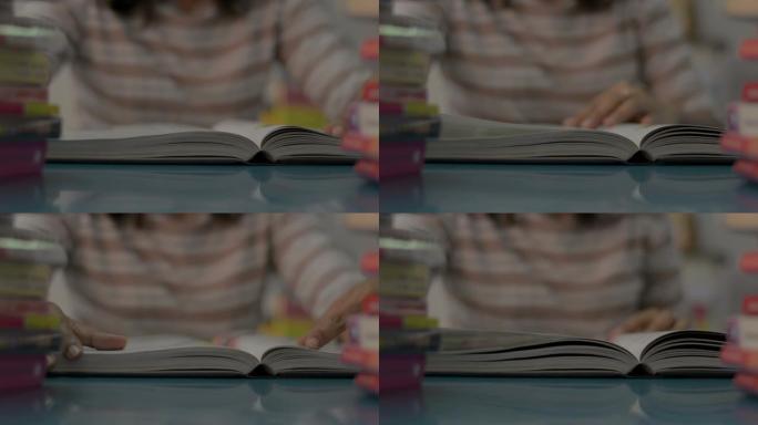 女孩翻一页，在家里的桌子上放着一叠书，读一本教科书。