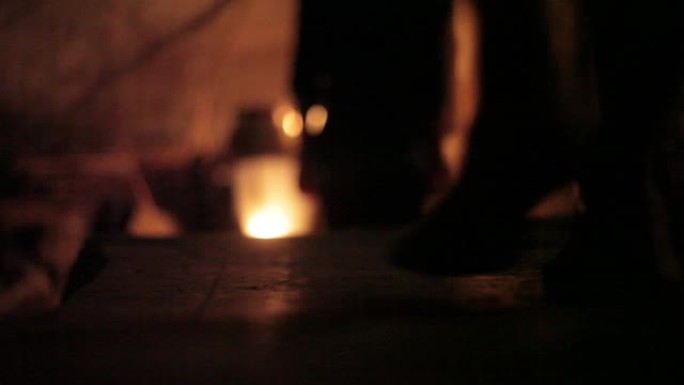 在令人毛骨悚然的黑暗位置使用蜡烛照亮了走下楼梯的人形/身体的轮廓。