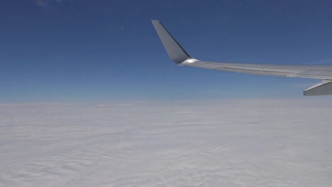 通过飞机窗户观看云层上方的飞机机翼