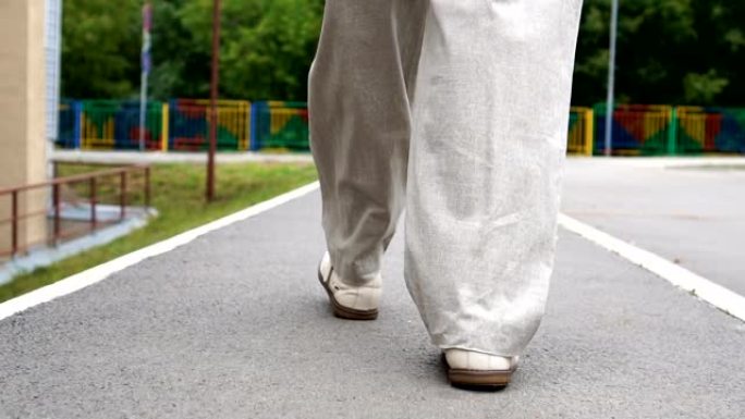 男人穿着鞋子在瓷砖路上行走的镜头。城市环境
