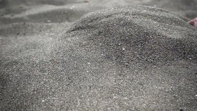 慢动作手舀起一把沙子，把它洒了出来