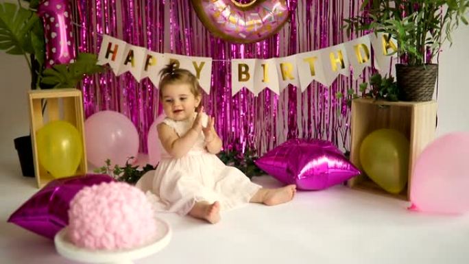 微笑的女婴在生日蛋糕前鼓掌