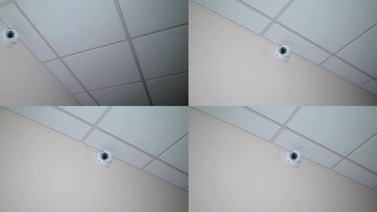 闭路电视位于天花板下的墙壁上，白色圆形监控摄像头