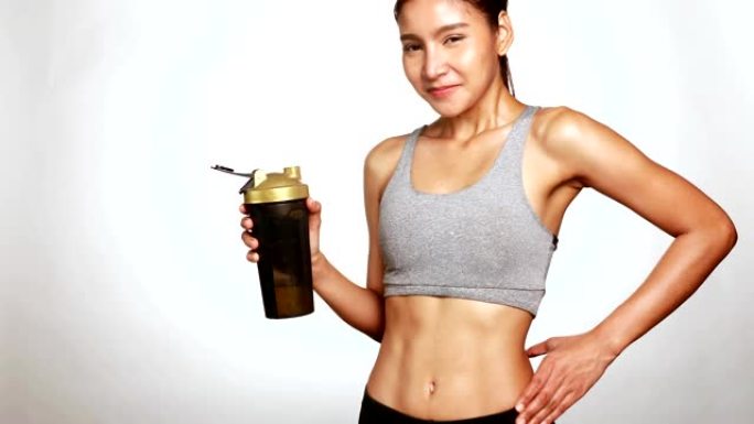 穿着运动服的苗条完美女性身体喝乳清蛋白补充剂，用于健身和饮食控制
