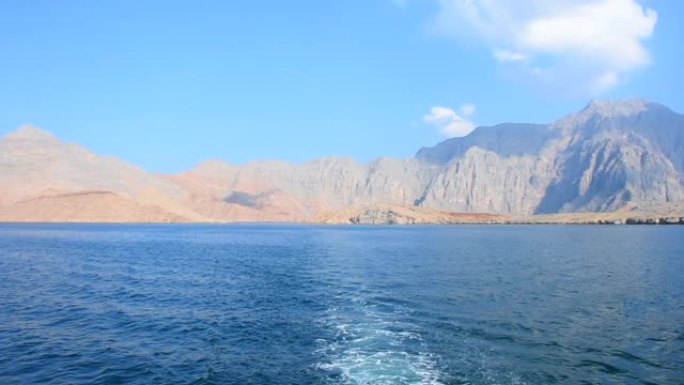 度假时在阿曼穆桑达姆的壮观风景全景，游船穿越峡湾、落基山脉和中东霍尔木兹海峡附近的蓝水。