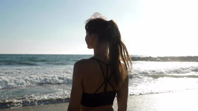 运动女子在海滩上放松身心，并在锻炼后欣赏美景