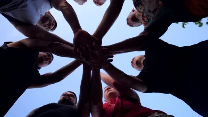 年轻的运动员们团结一致地将他们的双手一一叠在一起。一群最好的朋友把他们的手臂放在一个圆圈的中心，把他
