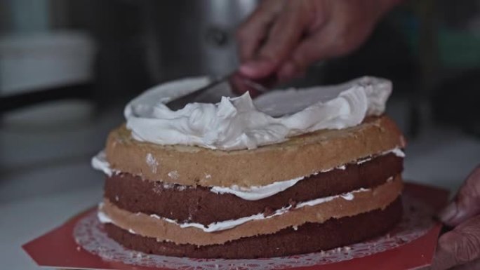 将奶油放在巧克力海绵蛋糕上的特写镜头。