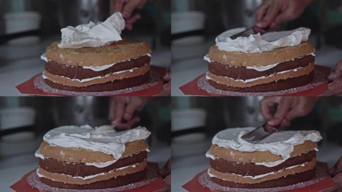 将奶油放在巧克力海绵蛋糕上的特写镜头。