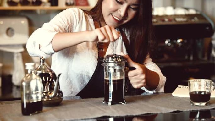 亚洲专业女咖啡师作为店主在自助餐厅的柜台酒吧用拿铁艺术咖啡倒牛奶。煮咖啡的女服务员。人们的生活方式和