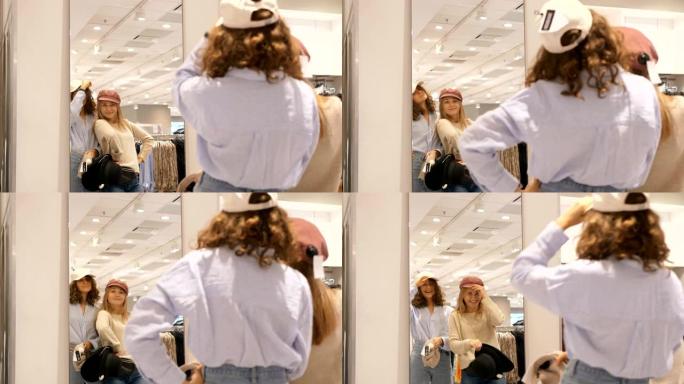 有趣的最佳女友在镜子前的服装店里试戴帽子，然后大笑