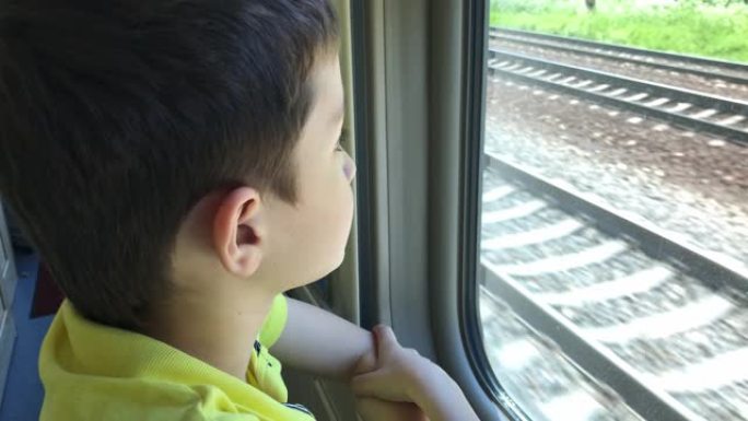 一个十几岁的男孩在乘坐火车时透过窗户看着风景