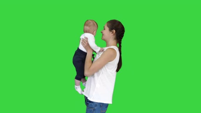 快乐的母亲在绿色屏幕上亲吻可爱的婴儿，色键