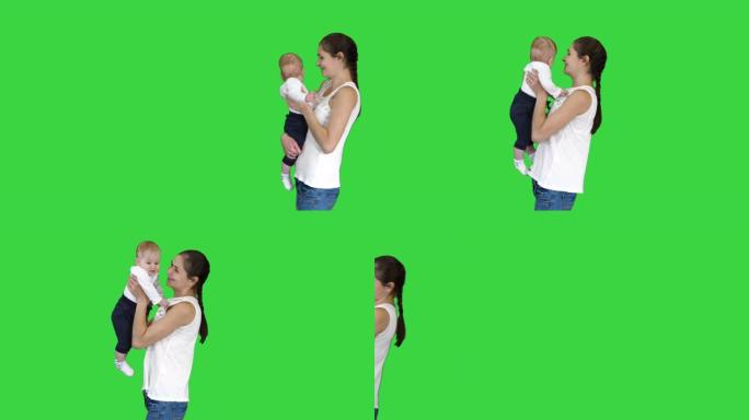 快乐的母亲在绿色屏幕上亲吻可爱的婴儿，色键