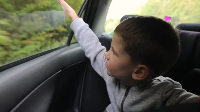 小男孩将手臂伸出车窗