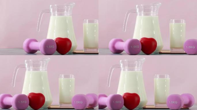 在粉红色背景上关闭装有玻璃牛奶和哑铃的罐子。早餐健康，锻炼健康。多莉拍摄幻灯片