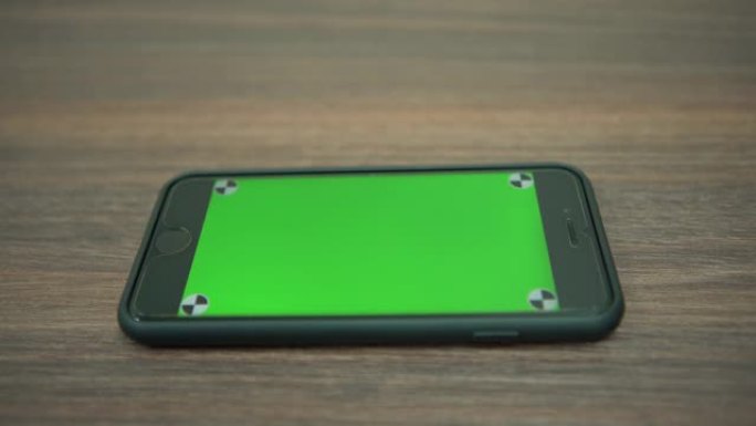 商务办公室木桌上绿屏智能手机的4k特写
