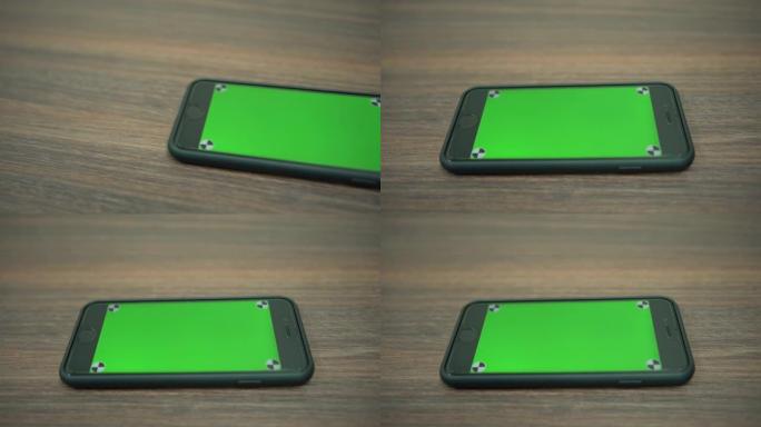 商务办公室木桌上绿屏智能手机的4k特写