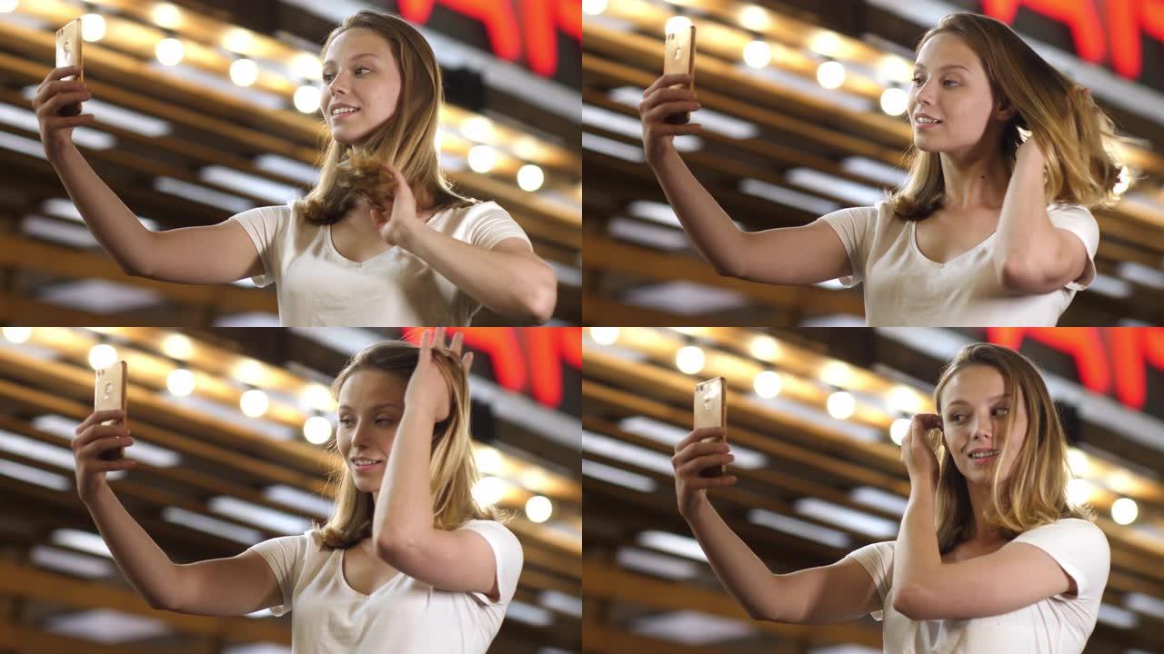 美丽的女人用智能手机当镜子刷头发