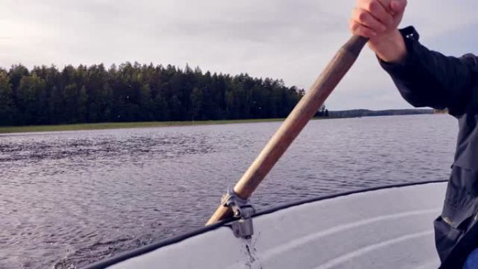 一个年轻人漂浮在湖上的船上。排桨。